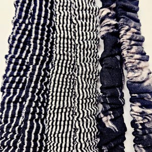 Puede incluir: Primer plano de cuatro coleteros con varios dise&ntilde;os. Los coleteros presentan rayas blancas y negras y un dise&ntilde;o veteado en blanco y negro. Los coleteros est&aacute;n hechos de una tela suave y texturizada.