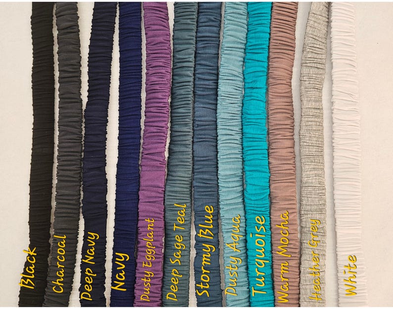 May include: A collection of eleven vertical fabric bands featuring a gathered, elasticized texture. The colors displayed from left to right are black, charcoal, deep navy, navy, dusty eggplant, deep sage teal, stormy blue, dusty aqua, turquoise, warm mocha, heather grey, and white.