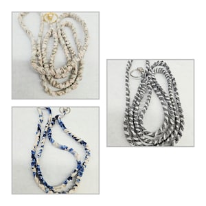 K&ouml;nnte beinhalten: Drei Stoff-Lanyards mit gedrehten Designs in Beige, Blau-Wei&szlig; und Schwarz-Wei&szlig;. Jedes Lanyard verf&uuml;gt &uuml;ber einen Metallring am oberen Ende und zeigt eine gewickelte Textilkonstruktion mit unterschiedlichen Farbmustern.