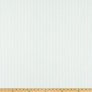 May include: White fabric with vertical, light blue stripes. The stripes are evenly spaced and run the length of the fabric. A wooden ruler is at the bottom of the image, providing scale.