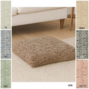 Puede incluir: Un cojín de suelo cuadrado con un diseño de patrón marrón y blanco. El cojín está colocado sobre una alfombra de color claro. La imagen también muestra muestras de color etiquetadas como "Fog", "Roebuck", "Falls", "Black", "Green" y "Sandstone".