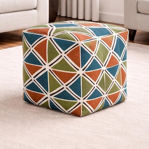 Puede incluir: Un puf cuadrado con un patrón geométrico en tonos turquesa, naranja, verde y blanco. El patrón consiste en triángulos y líneas curvas. El puf está colocado sobre una alfombra de color claro.