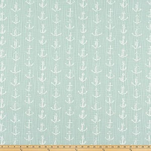May include: A light blue fabric with a repeating pattern of white anchors. The anchors are evenly spaced across the fabric, creating a nautical theme. The fabric has a textured appearance.