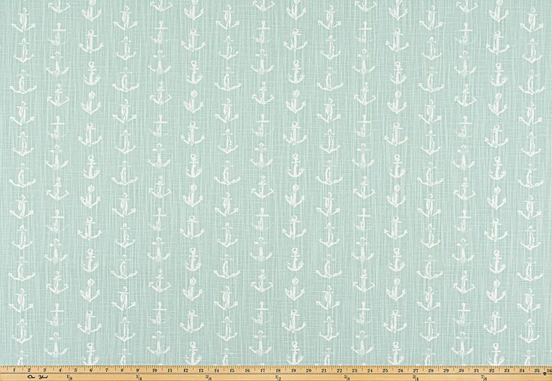 May include: A light blue fabric with a repeating pattern of white anchors. The anchors are evenly spaced across the fabric, creating a nautical theme. The fabric has a textured appearance.