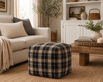 Peut inclure: Un pouf carré arborant un motif à carreaux classique dans des tons de noir, blanc et beige. Le tissu est tissé serré avec un design en grille, créant une forme structurée et cubique qui repose près du sol comme un meuble fonctionnel.
