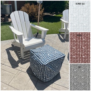 May include: A white adirondack chair with a navy blue and white patterned ottoman. The ottoman has a geometric pattern of white brushstrokes on a navy blue background. The chair and ottoman are on a gray patio.