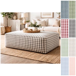 Puede incluir: Un gran otomán cuadrado tapizado en tela de cuadros grises y blancos. El otomán se encuentra sobre una alfombra de yute tejida en un salón. Se muestran muestras de tela adicionales en varios colores a la derecha.