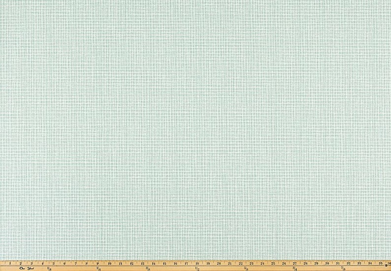 May include: A close-up of a light blue fabric with a grid pattern. The fabric has a textured appearance and is laid out on a wooden measuring board. The grid pattern is made up of thin white lines.