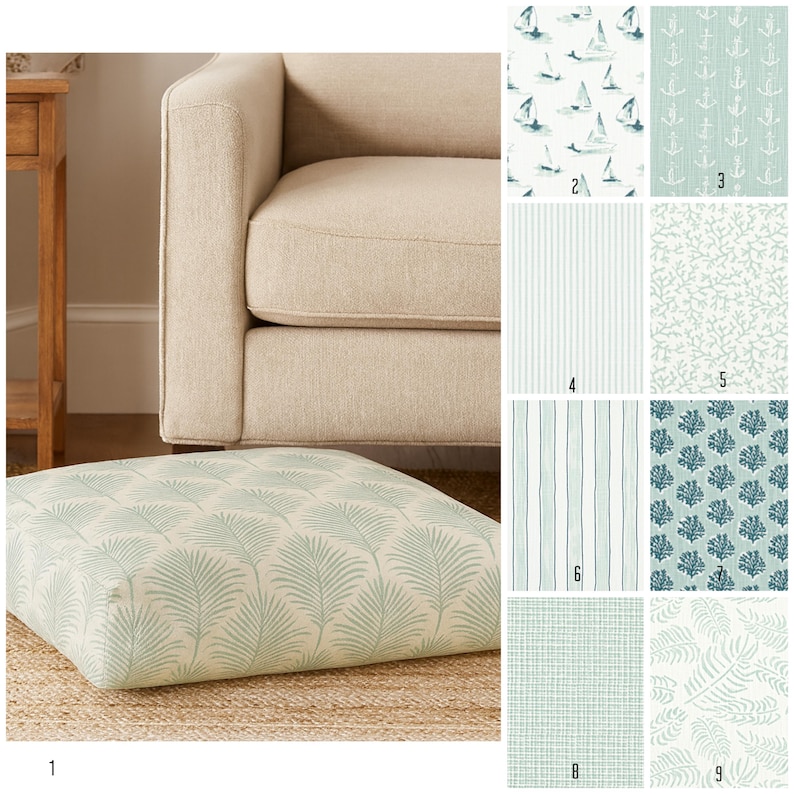 May include: A square floor cushion with a light green palm leaf pattern. The cushion is on a woven rug, with a beige armchair and various fabric swatches in the background. The swatches feature nautical and botanical designs.