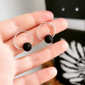 May include: A pair of silver hoop earrings with a black lava rock bead on each hoop.