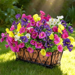 May include: A rectangular planter filled with colorful flowers in shades of purple, pink, yellow, and white. The flowers are in a brown woven basket with a black metal frame, set on a grassy lawn.