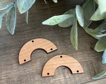 May include: Two unfinished wooden rainbow arches with four holes each. The arches are on a woodgrain surface.