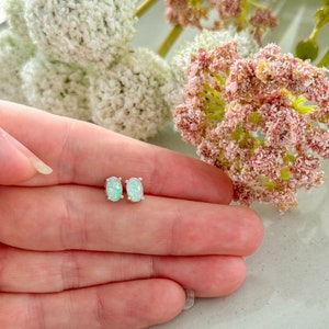 May include: A pair of silver stud earrings with oval-shaped white opal stones.