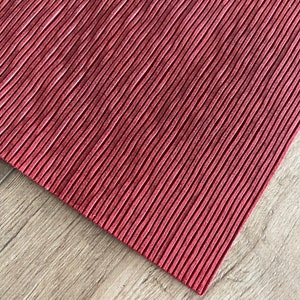 May include: Red ribbed placemat with a textured surface.