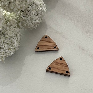 May include: Two wooden triangle shapes with three holes each. The triangles are a light brown color and have a wood grain pattern.