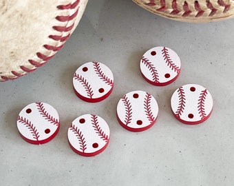 May include: Six white and red baseball-themed buttons with red stitching and two holes. The buttons are round and have a white background with red stitching and two red dots.