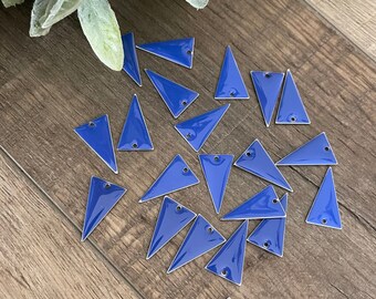 May include: A collection of blue triangle-shaped metal embellishments with a silver outline. The embellishments have a hole at the top for attaching to a project.
