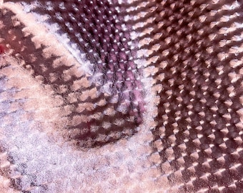 May include: Close-up of a textured, metallic, pink and silver fabric with a subtle diamond pattern.