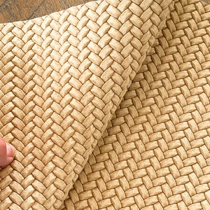 May include: Close-up of a woven fabric with a beige color. The fabric has a textured surface and a woven pattern.