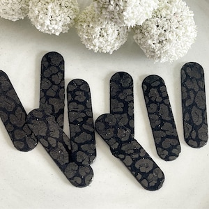 May include: Seven black and white leopard print nail file stickers. The stickers are rectangular and have a slightly rounded edge.