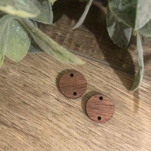 May include: Two round wooden circles with two holes each. The circles are a dark brown color and have a wood grain pattern.