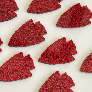 May include: Red glitter arrowhead shapes, perfect for crafting projects or adding a touch of sparkle to your decor.