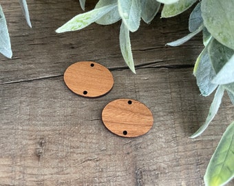 May include: Two unfinished wooden oval shapes with two holes each. The ovals are on a woodgrain surface.