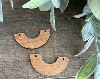 May include: Two unfinished wooden half-circle shapes with two holes each. The shapes are light brown and have a smooth surface.
