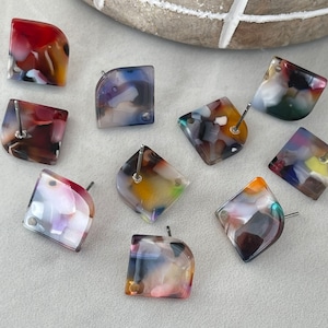 May include: Eight pairs of colorful, square-shaped earrings with a marbled pattern. The earrings are made of resin and have a silver post.
