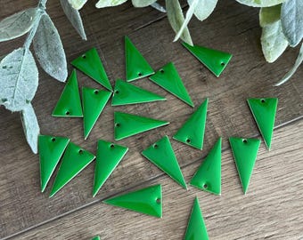 May include: A collection of small, bright green triangular charms, each featuring a smooth, glossy enamel finish and a single, centered hole at the top point for attachment. These flat, geometric metal pieces are scattered across the surface.