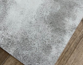 May include: A close-up of a gray textured surface with a white speckled pattern. The surface is smooth and has a subtle sheen.