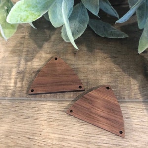 May include: Two unfinished wooden triangle shapes with rounded edges. Each triangle has three holes drilled into it.