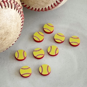 May include: Nine yellow and red softball-themed buttons with white stitching. The buttons are arranged in a semi-circle on a white surface.