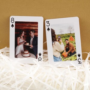 Puede incluir: Dos cartas de juego con fotos personalizadas. Una carta es el ocho de picas, que muestra a una pareja cortando un pastel. La otra es el tres de picas, con una persona tomando una foto de un hombre con una calabaza.