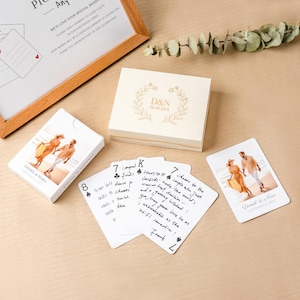May include: A custom deck of playing cards featuring a photo of a couple on the box and individual cards, a wooden storage box engraved with D&N 08.08.2025, and a framed sign with text inviting guests to leave notes on the cards for the couple.