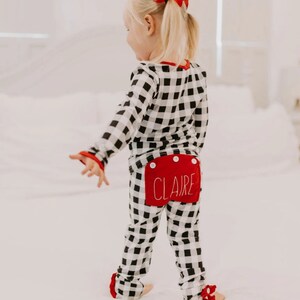May include: Black and white buffalo plaid pajamas with red trim and a red patch on the back that says "CLAIRE".