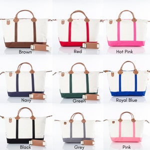 May include: A collection of canvas tote bags in various colors, including brown, red, hot pink, navy, green, royal blue, black, grey, and pink. Each bag has a white body, colored accents, leather handles, and a matching shoulder strap.