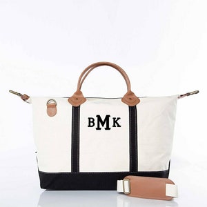May include: Cream-colored canvas tote bag with black accents and brown leather handles. The bag features the initials "BMK" in black block letters. Includes a detachable shoulder strap with a brown leather pad.