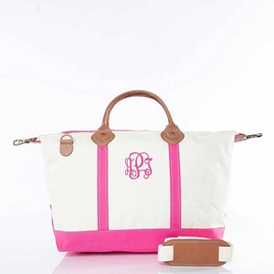 May include: White canvas tote bag with a hot pink base and vertical stripes. Features brown leather handles and accents, a detachable shoulder strap, and a monogram in the center. The bag has a classic, preppy style.