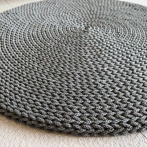 May include: A round gray braided rug with a textured surface.