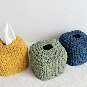 Puede incluir: Tres cubiertas de caja de pañuelos de tejido de crochet en diferentes colores: amarillo mostaza, verde salvia y azul marino. Las cubiertas son de forma cuadrada y tienen una abertura cuadrada en la parte superior para los pañuelos.