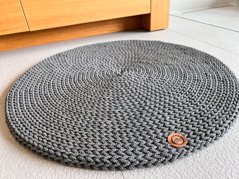 May include: A gray round crocheted rug with a brown button in the center.