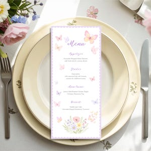 May include: A table setting with a menu card featuring a butterfly design. The menu, with a lilac border, lists appetizers, starters, main course, and dessert. The table is set with cream-coloured plates, silverware, and a floral arrangement.