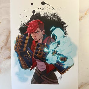 Può includere: Illustrazione di un personaggio con i capelli rossi, che indossa una giacca rossa e guanti blu e oro. Il personaggio è ambientato su uno sfondo nero di schizzi di inchiostro con un effetto energia blu. L'opera d'arte è su sfondo bianco.