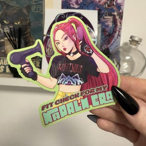 Può includere: Un adesivo con un'illustrazione a cartoni animati di una donna con i capelli rosa che tiene in mano un asciugacapelli viola. Indossa una maglietta nera con la scritta "MONTVIMISS" e l'adesivo recita "FIT CHECK FOR MY NAPALM ERA".