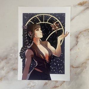 Può includere: Una stampa artistica raffigurante una donna con capelli scuri e orecchie a punta, che guarda verso l'alto. Indossa un abito scuro con dettagli dorati, tenendo una stella geometrica su uno sfondo di cielo stellato. Tema fantasy.