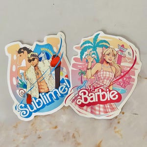 Puede incluir: Dos pegatinas troqueladas. Una presenta a un hombre de dibujos animados con gafas de sol y la palabra "Sublime!" en azul. La otra pegatina dice "Hi Barbie" y representa a una mujer con un vestido de cuadros rosa. Ambas pegatinas tienen un estilo de dibujos animados colorido.