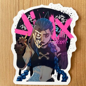 May include: A sticker featuring a cartoon illustration of a female character with blue hair and a black and white outfit. The character is wearing a mask with a gold and yellow design. The background is black with pink graffiti and the word "BOOM" in pink.
