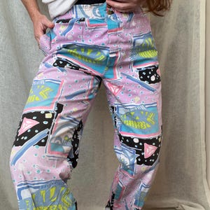 May include: A pair of light pink trousers with a geometric print in shades of blue, green, black, and white.