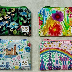 Op de afbeelding: Vier kleine, rechthoekige etuis met ritssluiting met bloemen- en reisthema's. De etuis hebben verschillende gekleurde ritsen en bevatten de nummers 33, 34, 35 en 36 op kleine witte labels.